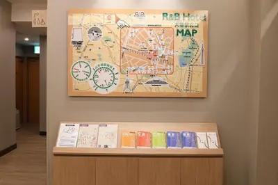 a map on a wall above a shelf with books at R&B Hotel Otsuka Eki Kitaguchi - Vacation STAY 14221v in Tokyo