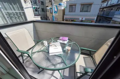 a glass table and chairs on a balcony with a book at Terrace house omori in Tokyo