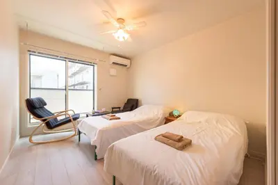 a bedroom with two beds and a chair and a window at Terrace house omori in Tokyo