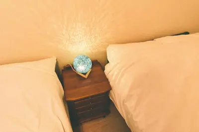 a nightstand with a clock on it between two beds at Terrace house omori in Tokyo