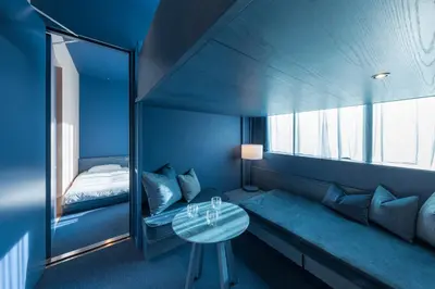 a blue room with a bed and a table at toggle hotel suidobashi TOKYO in Tokyo