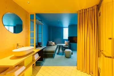 a yellow bathroom with a sink and a living room at toggle hotel suidobashi TOKYO in Tokyo