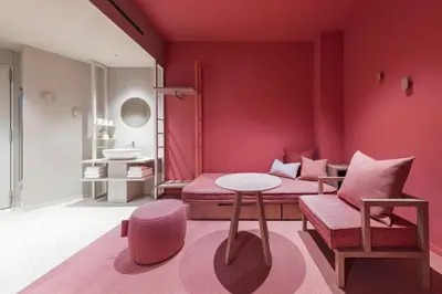 a pink room with a bed and a table and a chair at toggle hotel suidobashi TOKYO in Tokyo