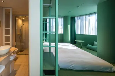 a green bedroom with a bed and a bathroom at toggle hotel suidobashi TOKYO in Tokyo