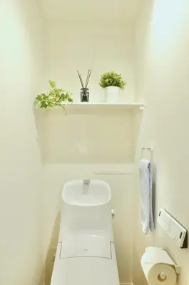 a bathroom with a toilet with two plants on a shelf at FL Residence Asakusa in Tokyo