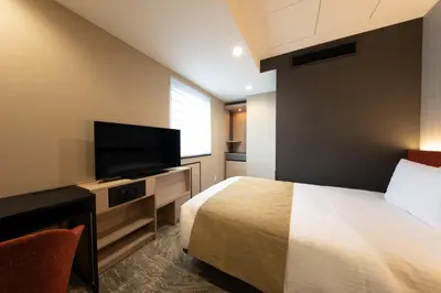 a hotel room with a bed and a flat screen tv at Almont Hotel Nippori in Tokyo