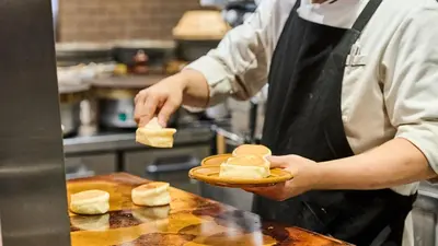 a man in a kitchen holding a plate of bread at DEL style Ikebukuro Higashiguchi by Daiwa Roynet Hotel in Tokyo