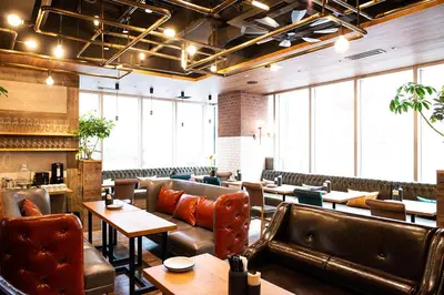 a restaurant with leather seats and tables and windows at DEL style Ikebukuro Higashiguchi by Daiwa Roynet Hotel in Tokyo