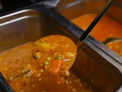 a spoon digging into a pot of food with stew at APA Hotel Ginza Kyobashi Minami Tokyo Station Yaesu South Gate in Tokyo