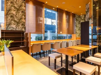 a restaurant with wooden tables and chairs and windows at APA Hotel Ginza Kyobashi Minami Tokyo Station Yaesu South Gate in Tokyo