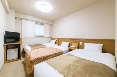 a hotel room with two beds and a flat screen tv at Pearl Hotel Ryogoku in Tokyo