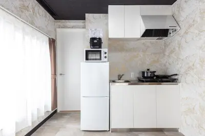 a kitchen with white cabinets and a refrigerator at Urban Stay Oshiage in Tokyo