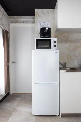 a white refrigerator with a microwave on top of it at Urban Stay Oshiage in Tokyo