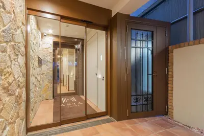 a hallway with a glass door and a stone wall at Asta Hotel in Tokyo
