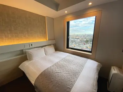 a bedroom with a white bed and a window at APA Hotel Keikyukamata Ekimae in Tokyo