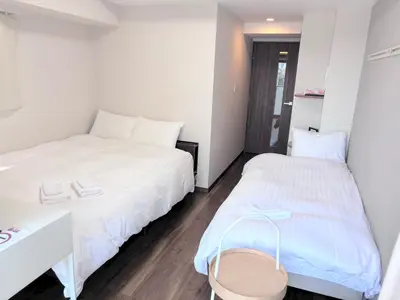 two beds in a small room with a desk and a bed at Otsuka No 4 Mansion in Tokyo