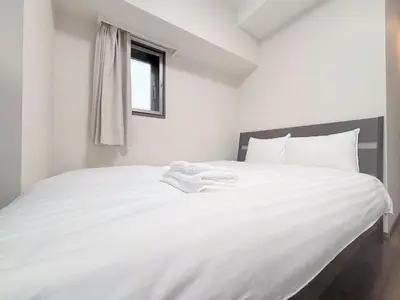 a white bed with white sheets and a window at Otsuka No 4 Mansion in Tokyo