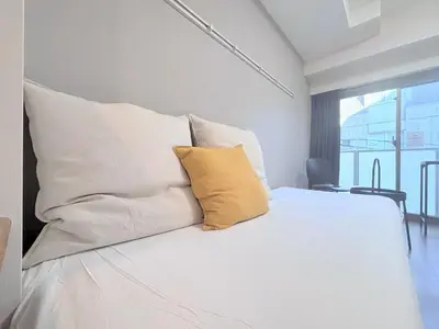 a white bed with a yellow pillow on it at Otsuka No 4 Mansion in Tokyo
