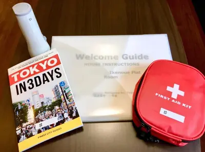 a book and a red suitcase next to a welcome guide at T-BASE - Vacation STAY 21950v in Tokyo
