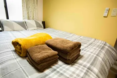 a bed with a pile of towels on it at Papa201 in Tokyo