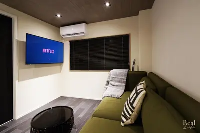 a living room with a green couch and a television at Real Life SANGENJAYA in Tokyo