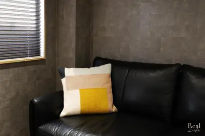 a black leather couch with a yellow and white pillow at Real Life SANGENJAYA in Tokyo