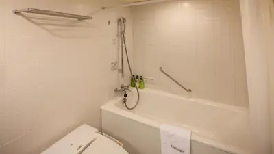 a white bathroom with a toilet and a bath tub at Odakyu Hotel Century Southern Tower in Tokyo