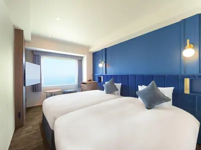 a hotel room with two beds and a blue wall at Oriental Hotel Tokyo Bay in Urayasu