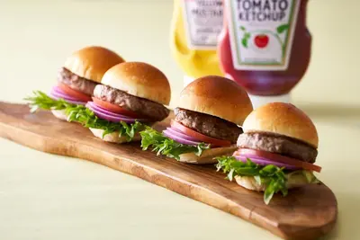 four hamburgers on a wooden cutting board with ketchup at Oriental Hotel Tokyo Bay in Urayasu