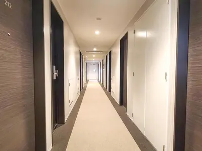 a hallway with white walls and a long hallway with black doors at HOTEL LiVEMAX Akasaka GRANDE in Tokyo