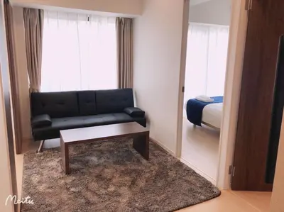 a living room with a black couch and a mirror at Hotel Emir in Tokyo