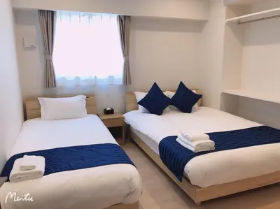 a bedroom with two beds with blue and white pillows at Hotel Emir in Tokyo