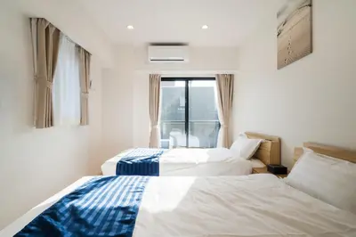 two beds in a room with a window at Hotel Emir in Tokyo