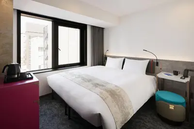 a bedroom with a large white bed and a window at the b ginza in Tokyo