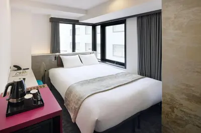 a hotel room with a large white bed and windows at the b ginza in Tokyo