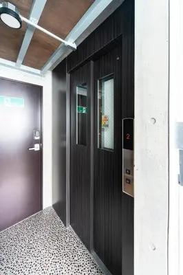 an empty corridor with a black door in a building at Oyado danran \u56e3\u6b12 in Tokyo