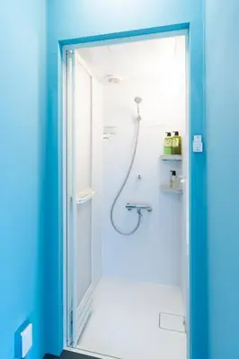 a bathroom with a shower with a blue wall at Oyado danran \u56e3\u6b12 in Tokyo