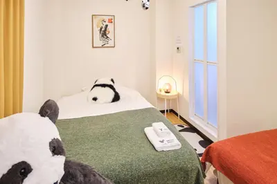 a bedroom with a teddy bear laying on a bed at TORA HOTEL Tokyo Ueno \u5bc5\u30db\u30c6\u30eb \u4e0a\u91ce A in Tokyo