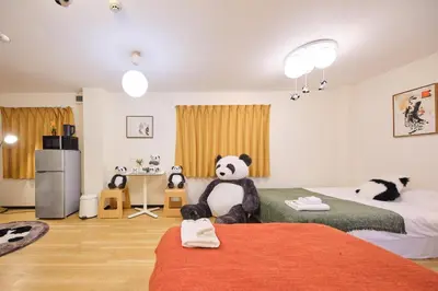 a room with two beds with a stuffed panda bear on the bed at TORA HOTEL Tokyo Ueno \u5bc5\u30db\u30c6\u30eb \u4e0a\u91ce A in Tokyo