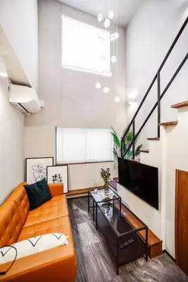 a living room with an orange couch and a tv at Ken's Place Azabudai in Tokyo
