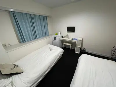 a hospital room with two beds and a desk and a monitor at Exsasion Sugamo in Tokyo