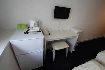 a room with a desk with a refrigerator and a chair at Exsasion Sugamo in Tokyo
