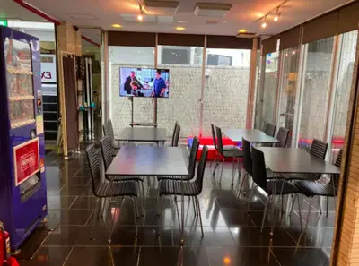 a dining room with tables and chairs and a tv at Exsasion Sugamo in Tokyo