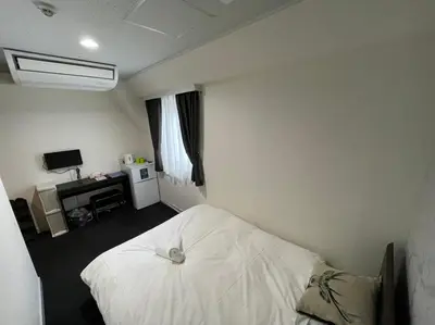 a bedroom with a white bed and a desk at Exsasion Sugamo in Tokyo