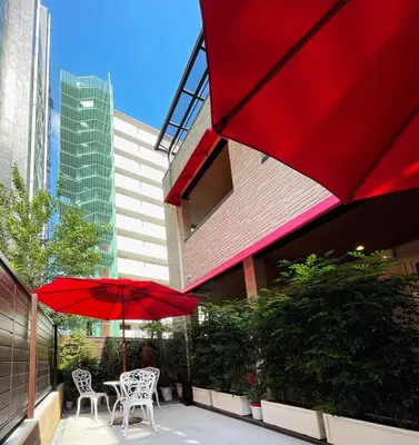 a patio with two tables and a red umbrella at SHINJUKU WARM HOUSE in Tokyo