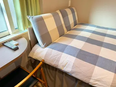 a bed in a room with a pillow and a table at SHINJUKU WARM HOUSE in Tokyo