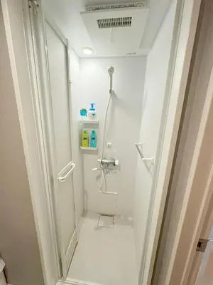 a white bathroom with a shower and a toilet at SHINJUKU WARM HOUSE in Tokyo