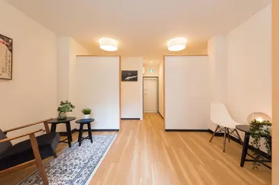 a living room with white walls and a table and chairs at TORA HOTEL Tokyo Ueno \u5bc5\u30db\u30c6\u30eb \u4e0a\u91ce C in Tokyo