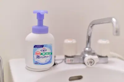 a bottle of sanitizer sitting on a bathroom sink at TORA HOTEL Tokyo Ueno \u5bc5\u30db\u30c6\u30eb \u4e0a\u91ce C in Tokyo