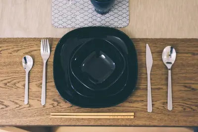 a table with a black plate and fork and knife at TORA HOTEL Tokyo Ueno \u5bc5\u30db\u30c6\u30eb \u4e0a\u91ce D in Tokyo